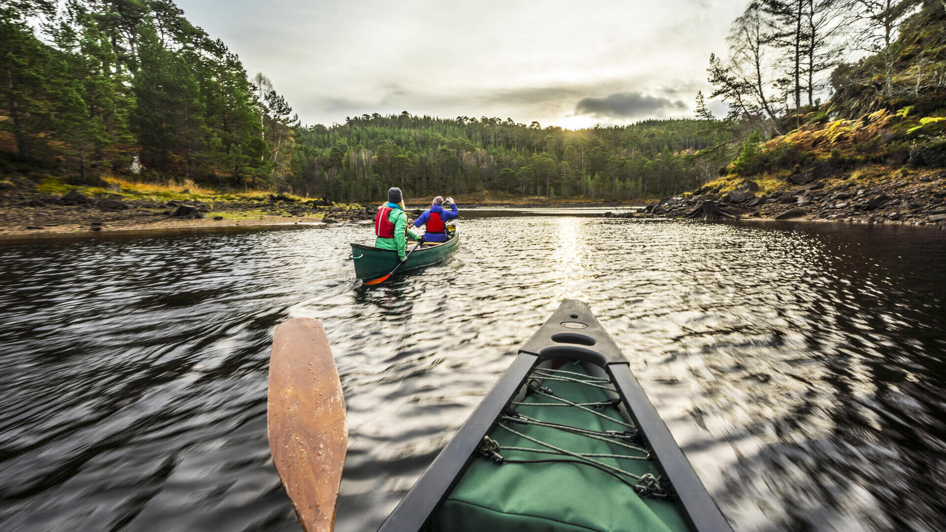 Two women paddling canoes on water