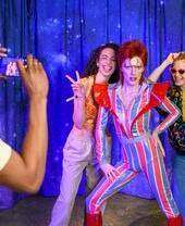 Des invités posent pour une photo avec la statue de David Bowie au musée Madame Tussauds de Londres
