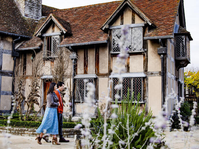 Couple walking through a garden of a Tudor building