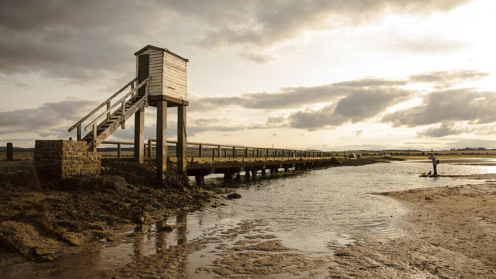 Two people by an elevated causeway at low tide