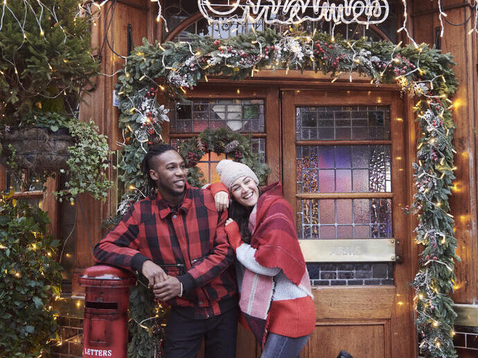 Couple in front of a pub entrance covered with Christmas decorations