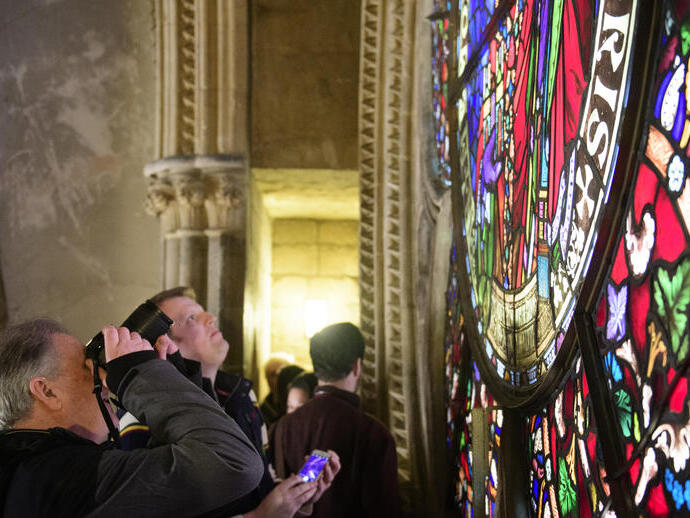 A tour group on a tour of Lincoln Cathedral, looking at a stained glass window