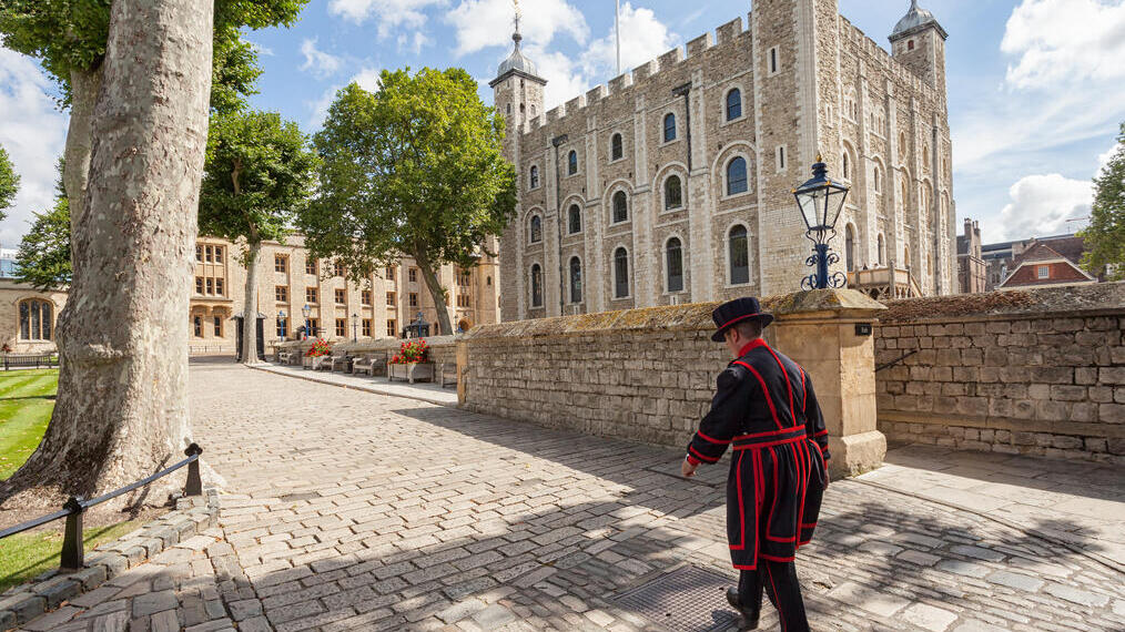 Beefeater walking by the Tower of London on a sunny day