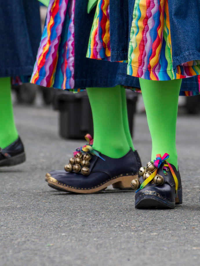 People in green tights and black shoes dancing at a folk festival.