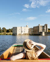 Woman in a punt on the moat looking towards castle