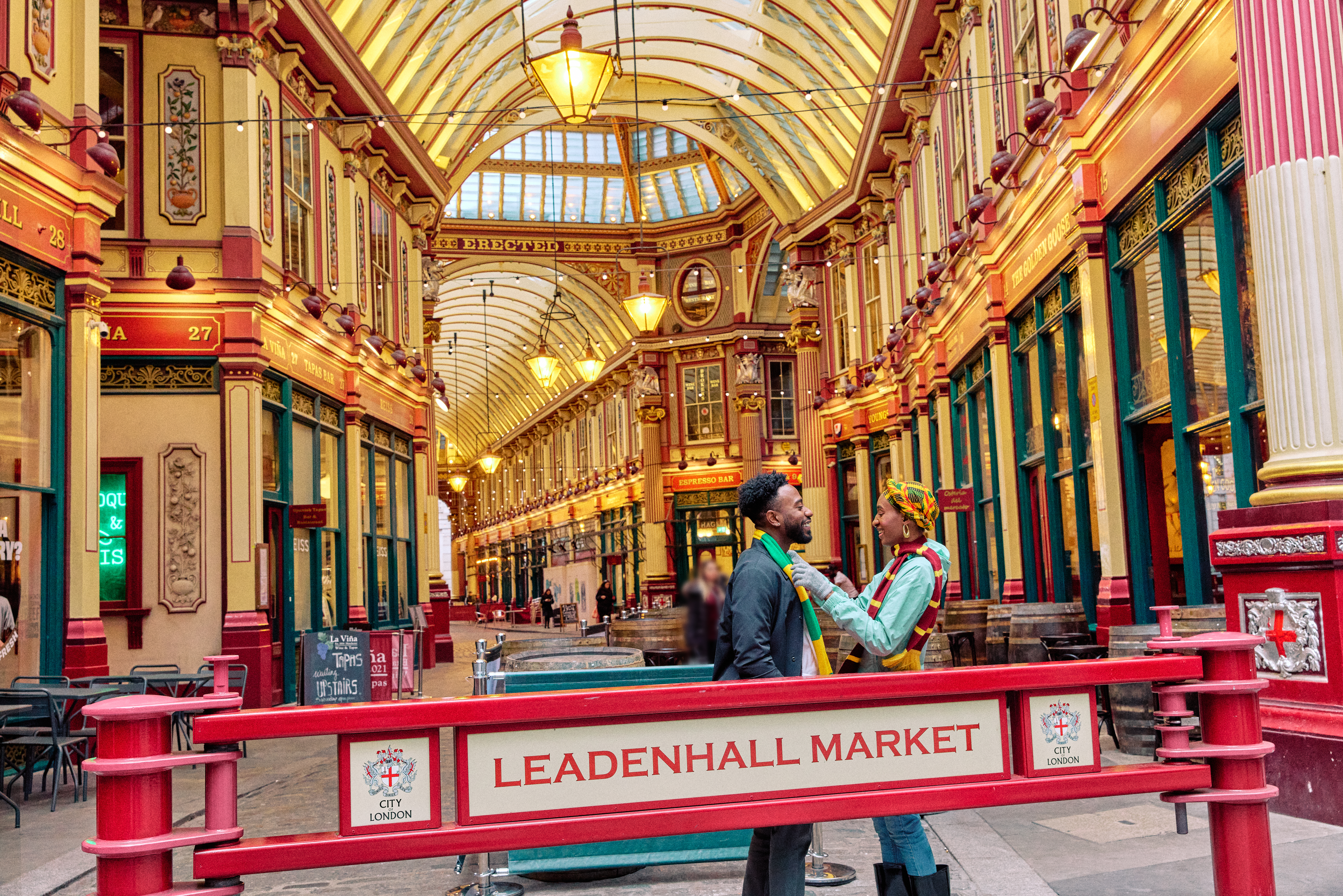 A couple joyfully play with colourful scarves outside market hall with a ornate decorated gold ceiling