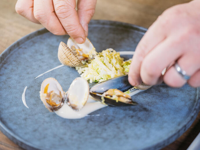 Close up of chef dressing plate with clams and scallops