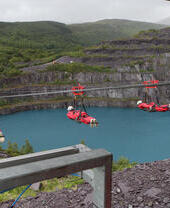 People ziplining across a large water filled quarry