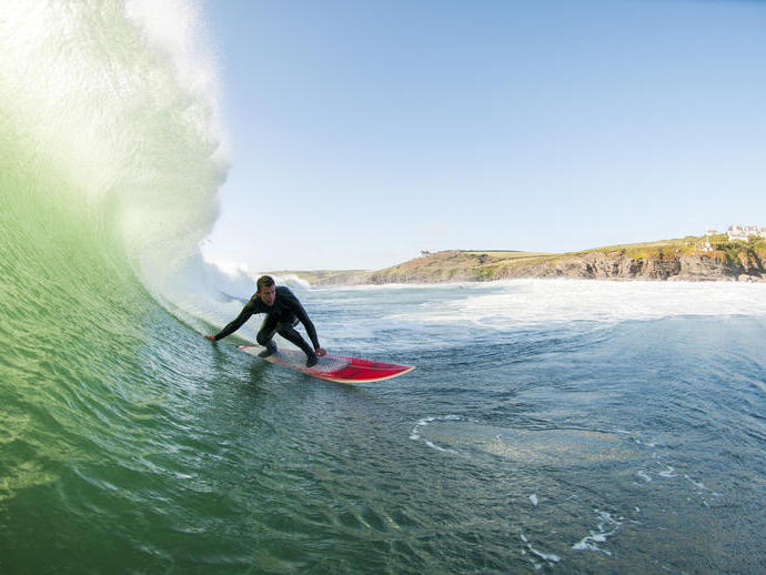 Surfer in a wetsuit surfing a large wave on a red surfboard in the sea