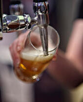 A person pouring a beer from a tapped keg