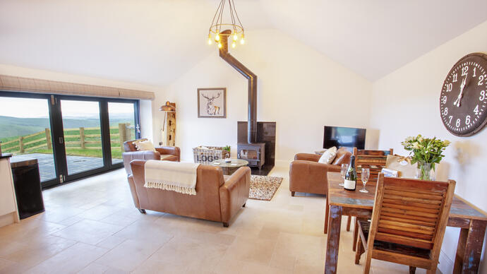 A living room with matching brown leather sofa and armchairs and a wood burner.