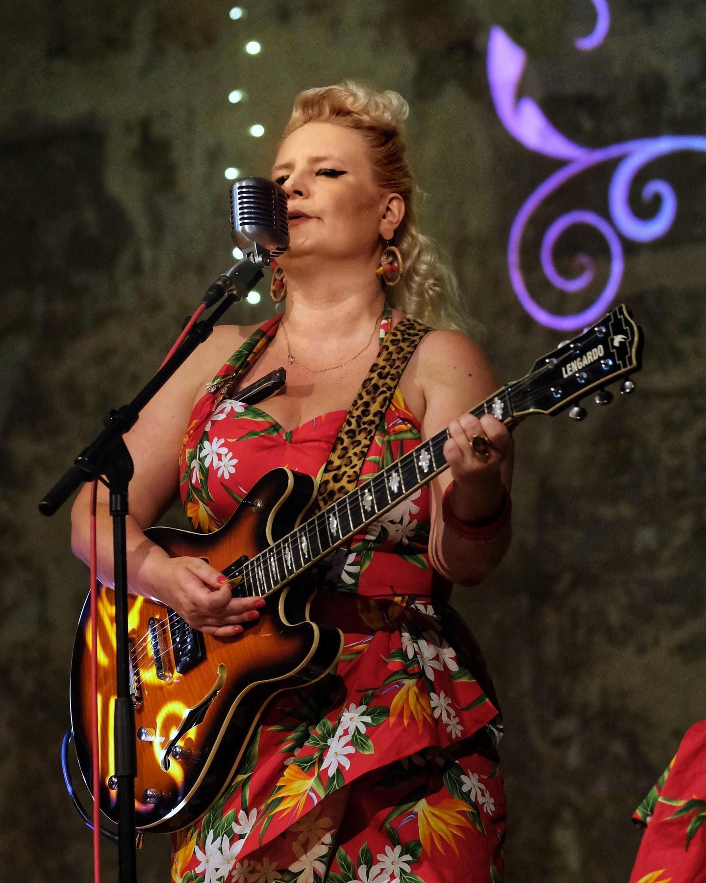 A lady singing and playing guitar at Wilton's Music Hall