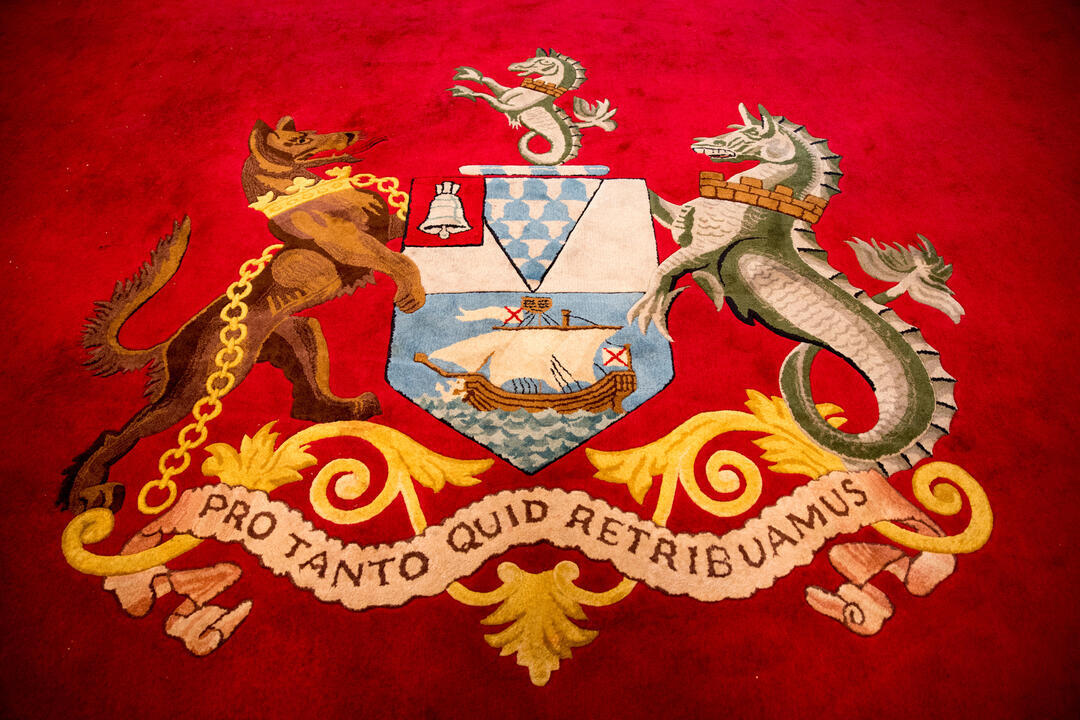 Carpet with coat of arms and motto.