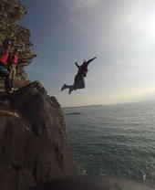 A group of people jumping from low cliffs into the sea near Snowdonia/Eryri National Park
