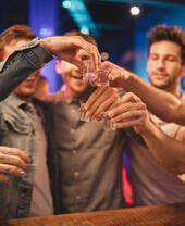 Group of men on a night out toasting their shots before drinking them, celebrating New Year