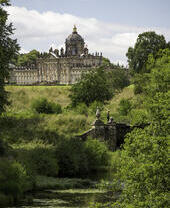 Großes Landhaus, umgeben von Bäumen, mit einem Bach im Vordergrund