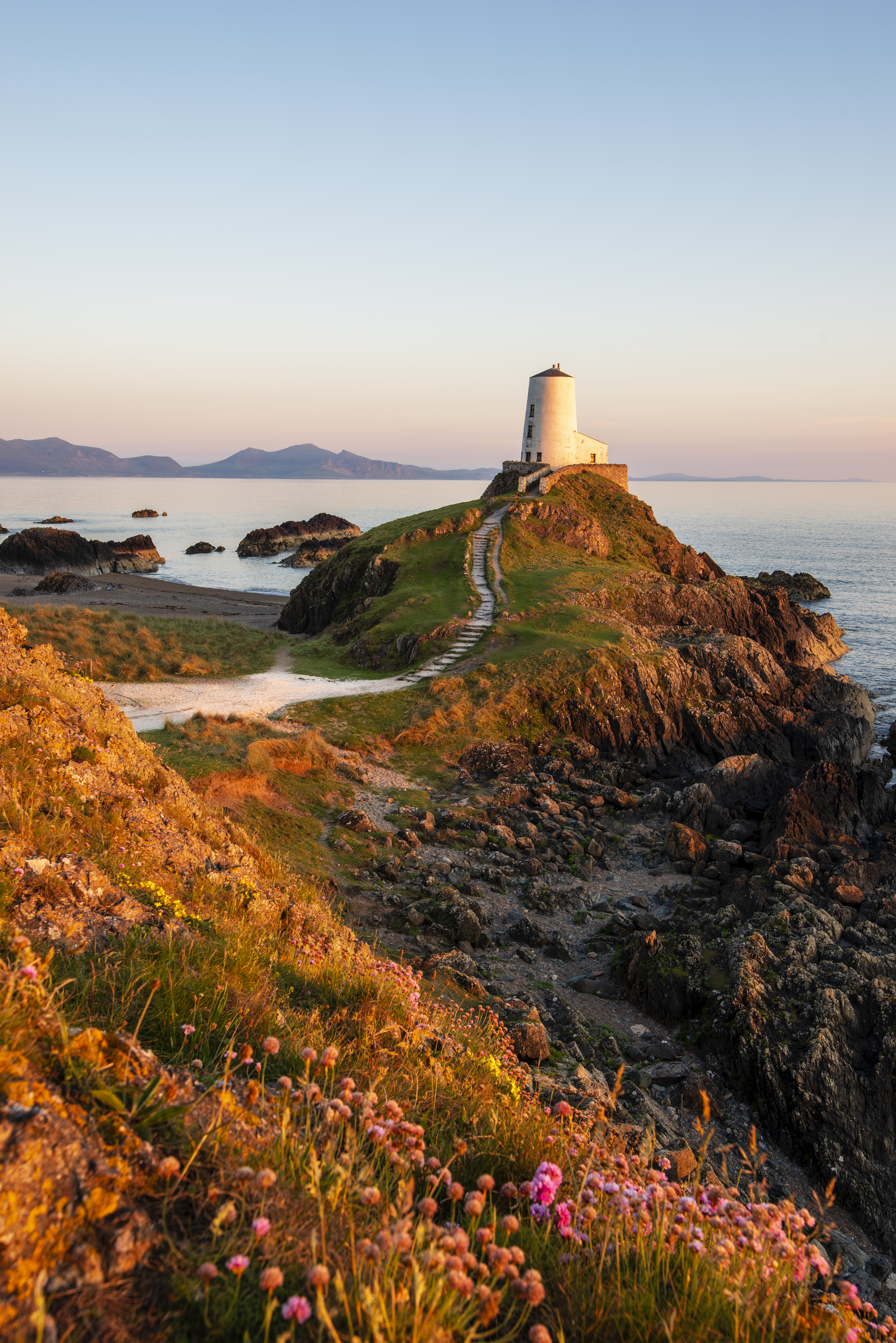 A path leading to a lighthouse on a prominent rocky outcrop by the sea