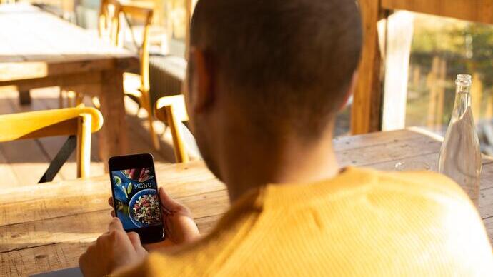 Male business owner looking at restaurant menu on smart phone