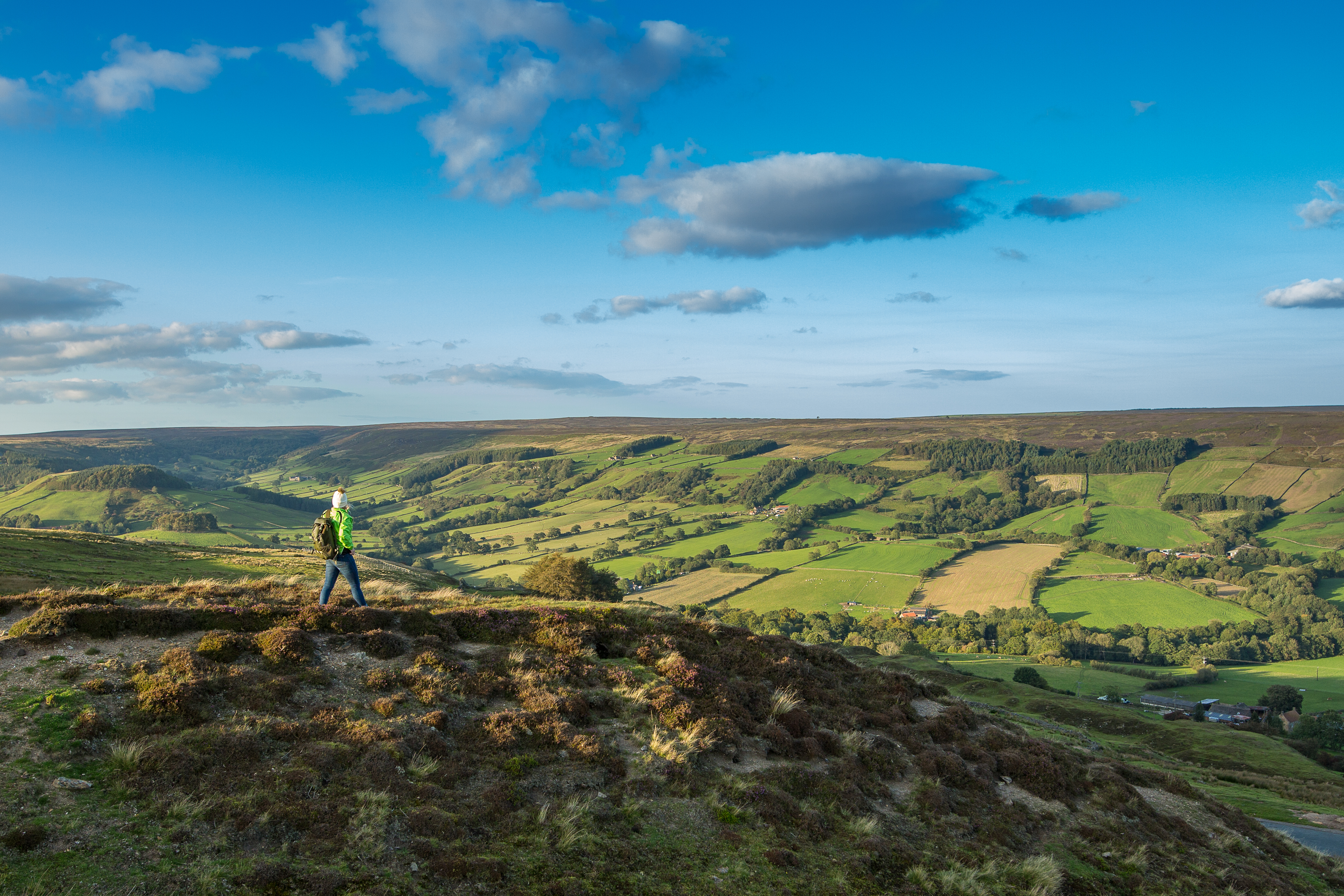 Eine Frau spaziert einen Pfad entlang auf einem Hügel und genießt die Aussicht.