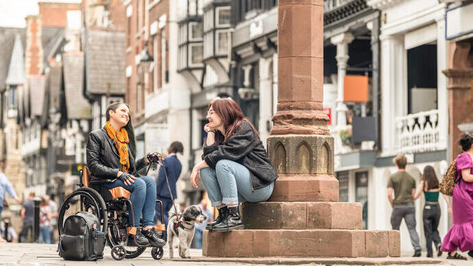 Two women sit talking together in a town centre