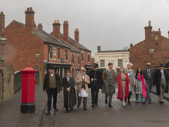Gruppo di persone che camminano su una strada in un museo vivente