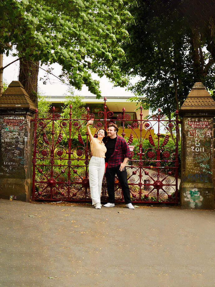Man and woman take pictures in front of the red gates at historic garden