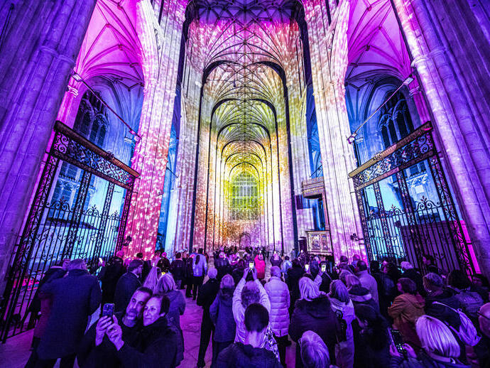 Group of people looking and photographing light show in a cathedral