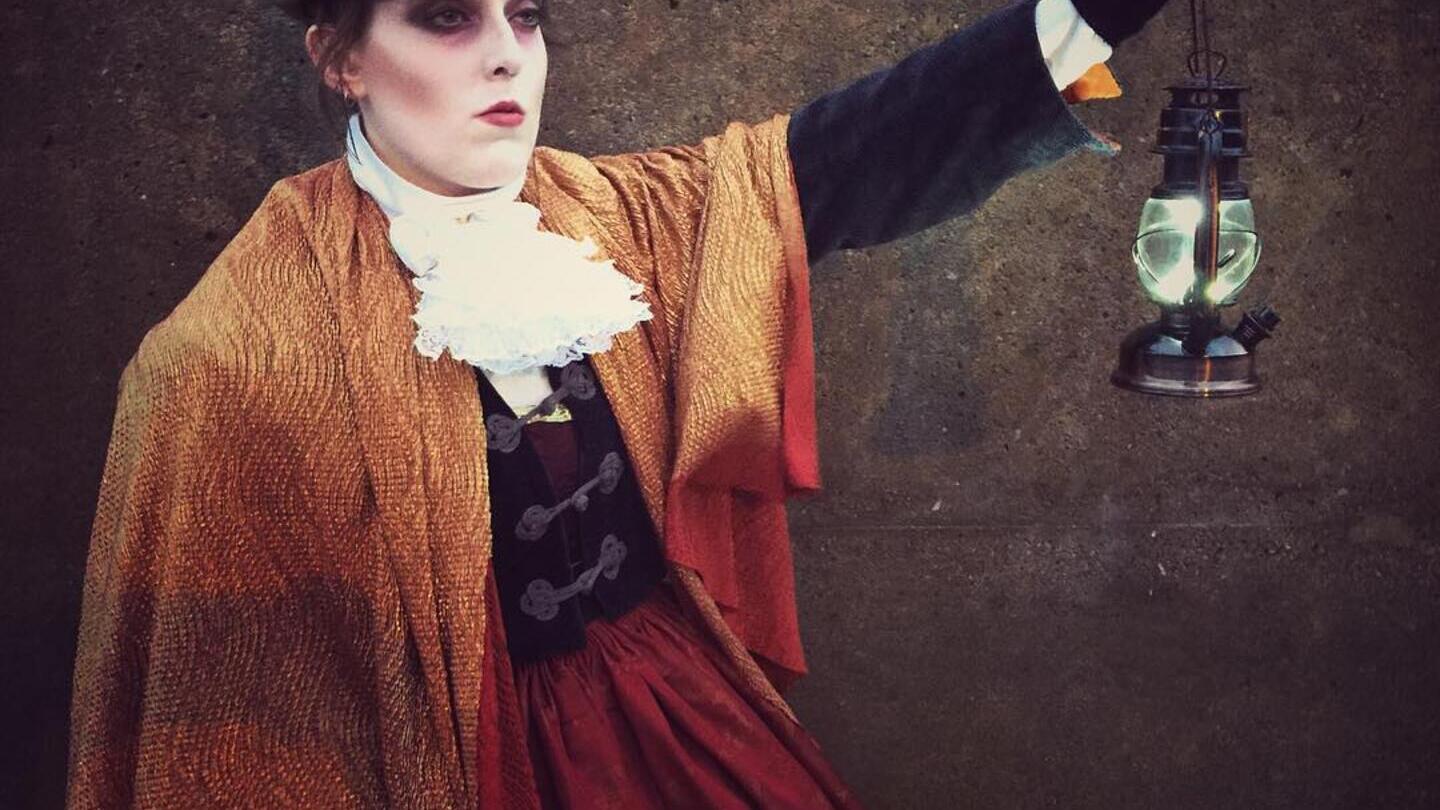 A lady holding a lantern on a ghost walk