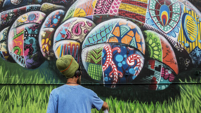 Ein Künstler, der mit Sprühfarbe ein Straßenkunstwerk gestaltet.