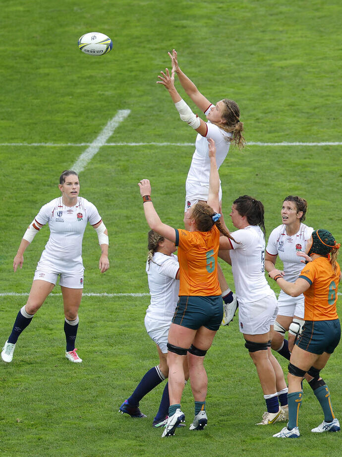Women's rugby match with players from two teams jumping to catch the ball on the field