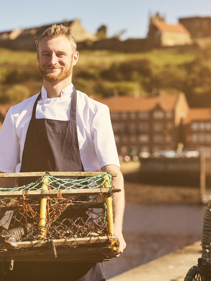 Homme tenant un casier à homards sur un quai au soleil