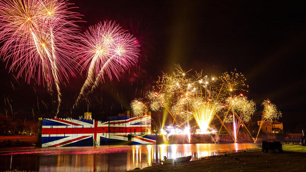 Fireworks and a large union jack illumination on a castle wall at night
