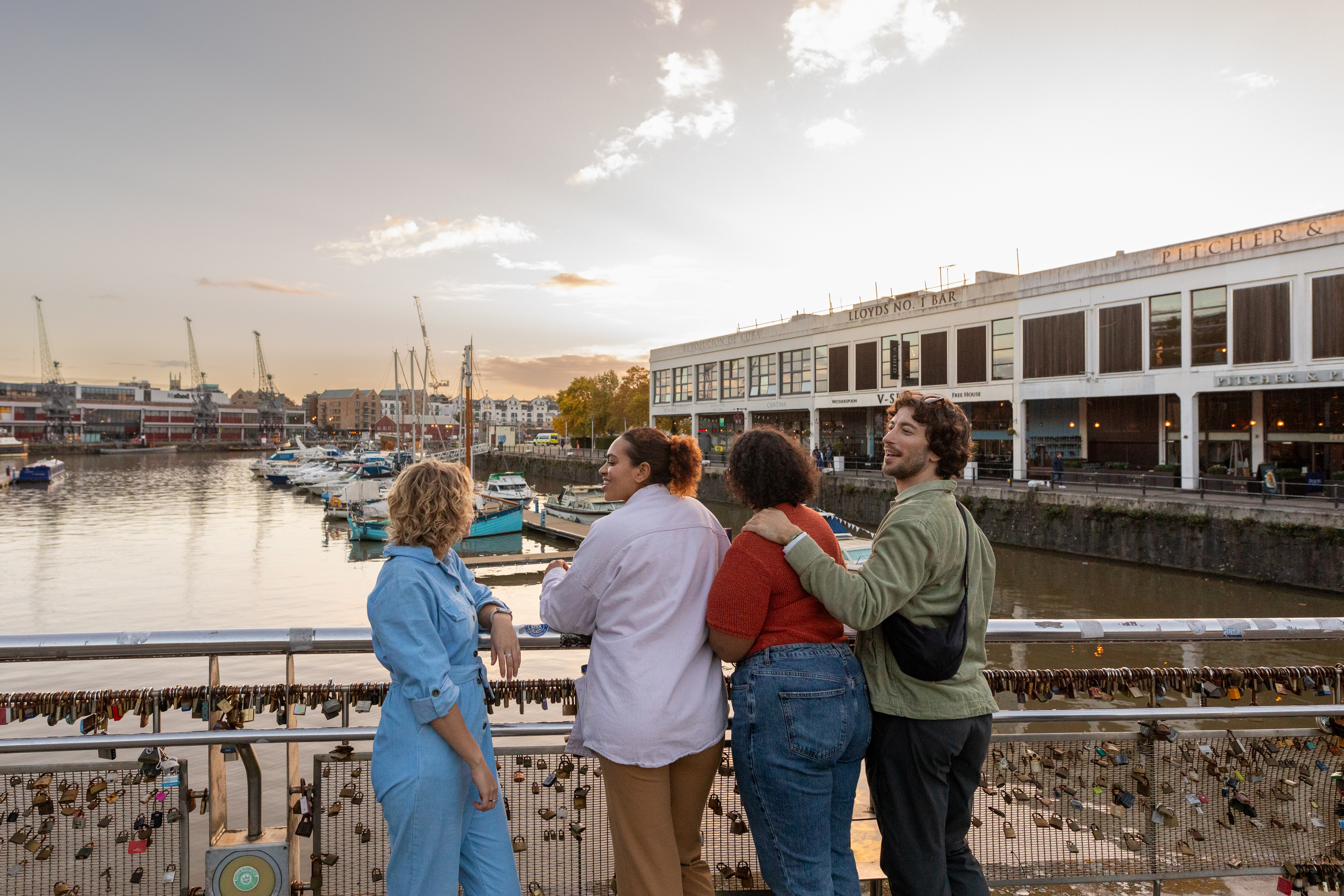 Friends walking over a waterfront bridge.