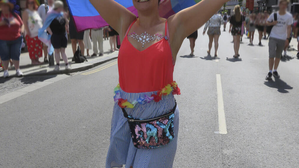 Mujer ondeando una bandera arcoíris durante el Orgullo