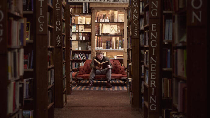 Mann in einer Buchhandlung, der ein Buch liest