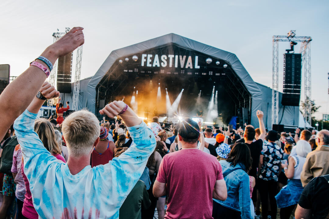 Large crowd dancing in front of a stage in the day at the Big Feastival in The Cotswolds.