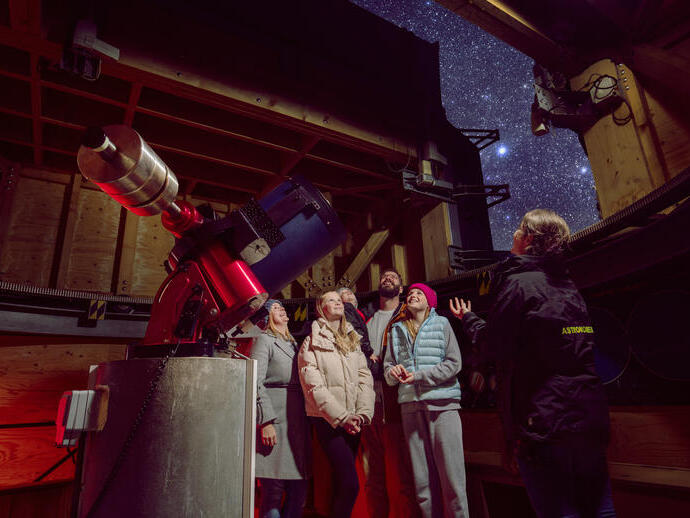 Eine Familie steht mit einem Reiseleiter vor einem Observatorium