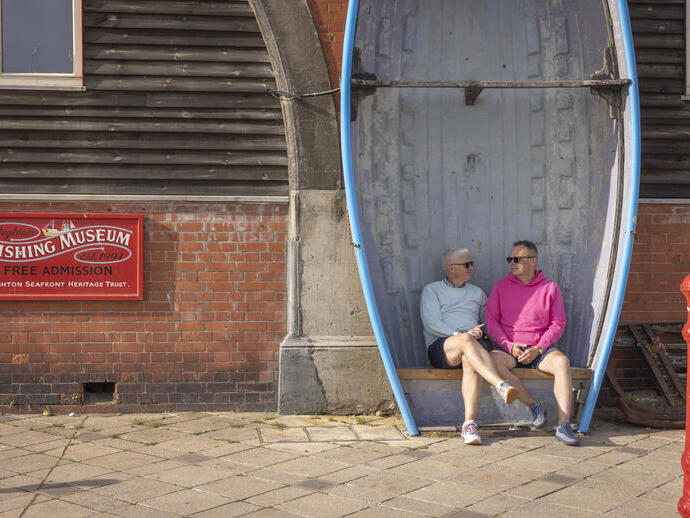 Zwei Männer sitzen auf einer Bank, die aus einem Ruderboot gefertigt wurde