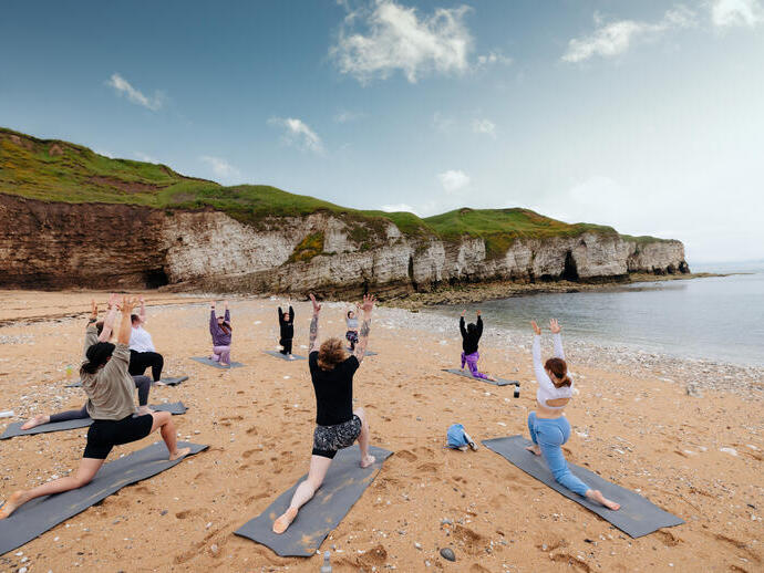 Un grupo de personas practicando yoga en la playa