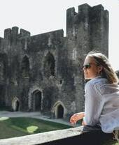 Una mujer con gafas de sol contemplando el castillo de Caerphilly, Gales