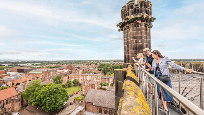 A group of people stand on a platform on the roof of a cathedral