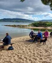 People eating at tables on a beach on the Isle of Arran