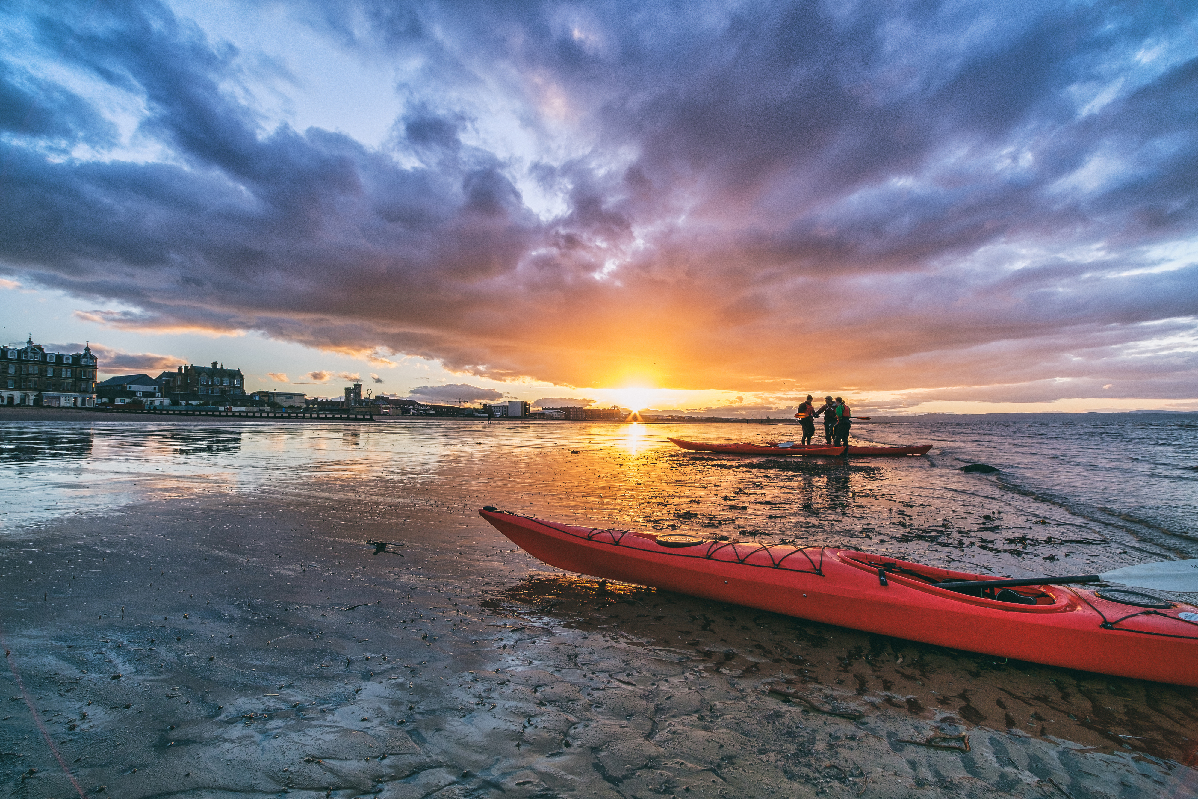 Kayaks and kayakers on beach at sunset. Portobello beach, Edinburgh