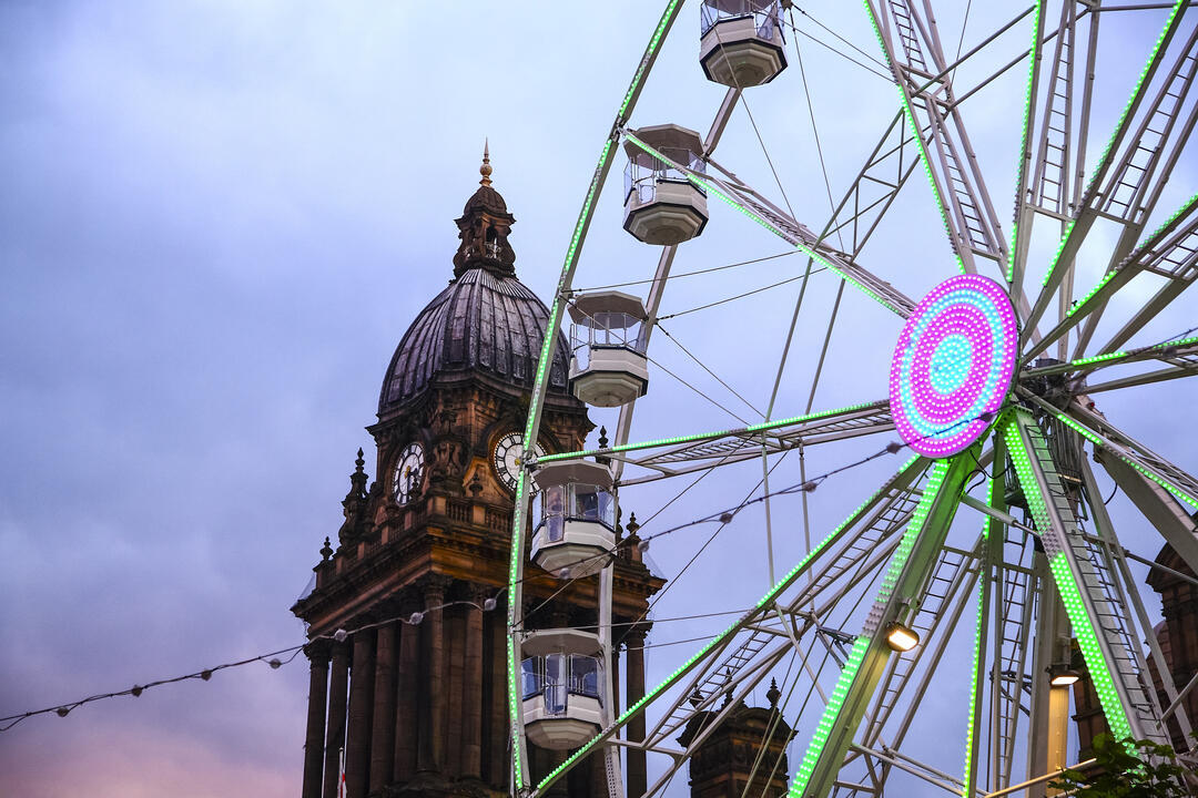 Looking up at clock tower and a Ferris wheel at dusk
