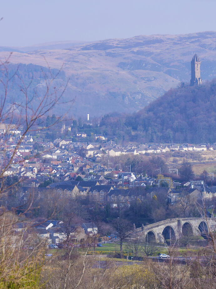 Aerial view of a town with a hilltop statue in the background.