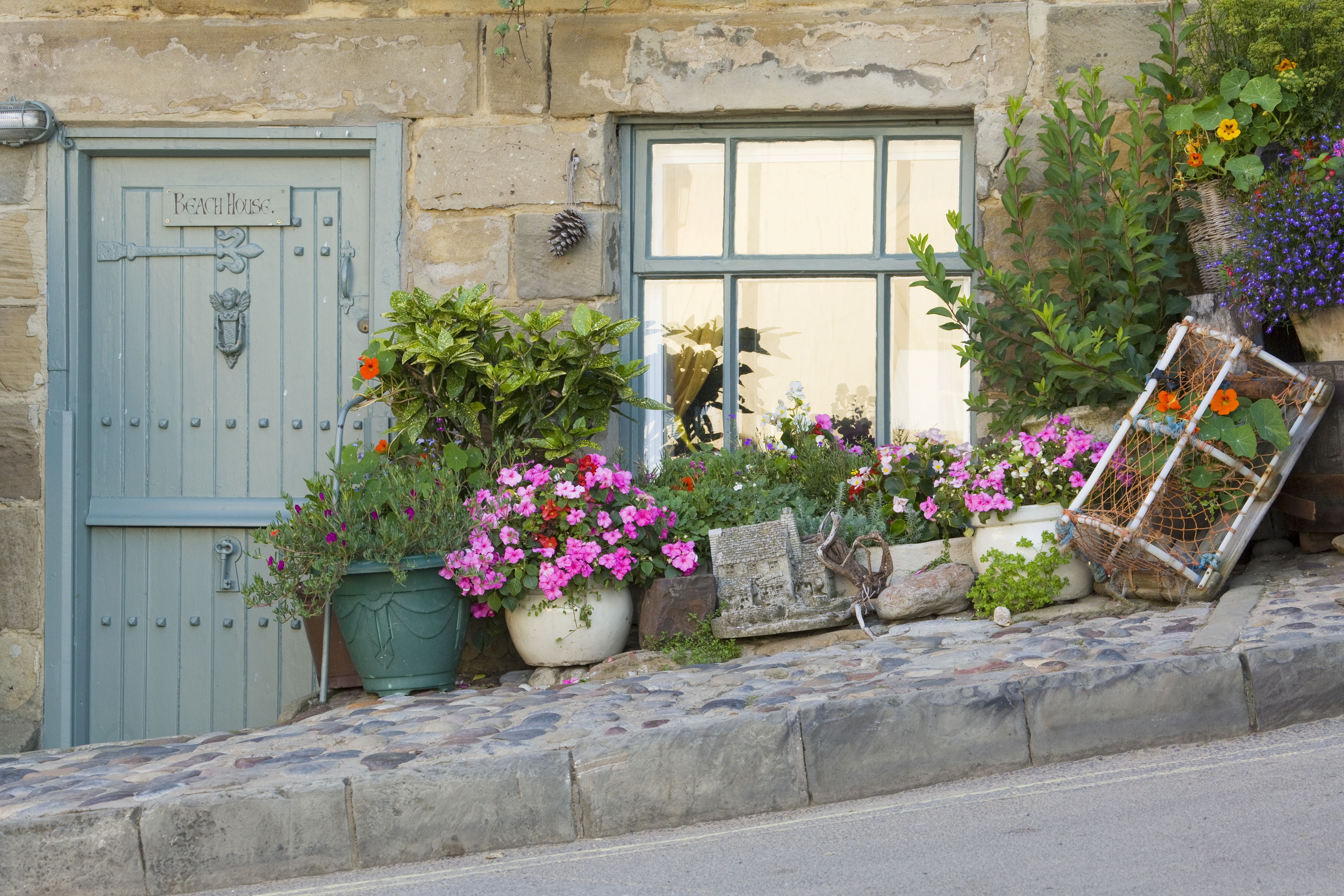 A cottage on a hill with plants in pots outside door