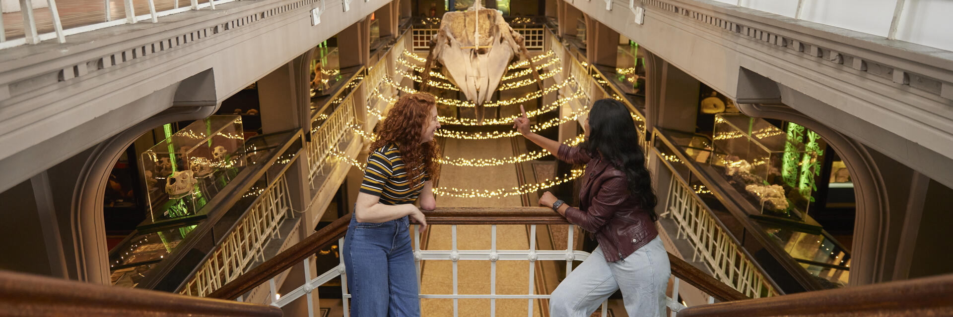 Dos mujeres charlan y ríen mientras visitan la exposición prehistórica en un gran museo.