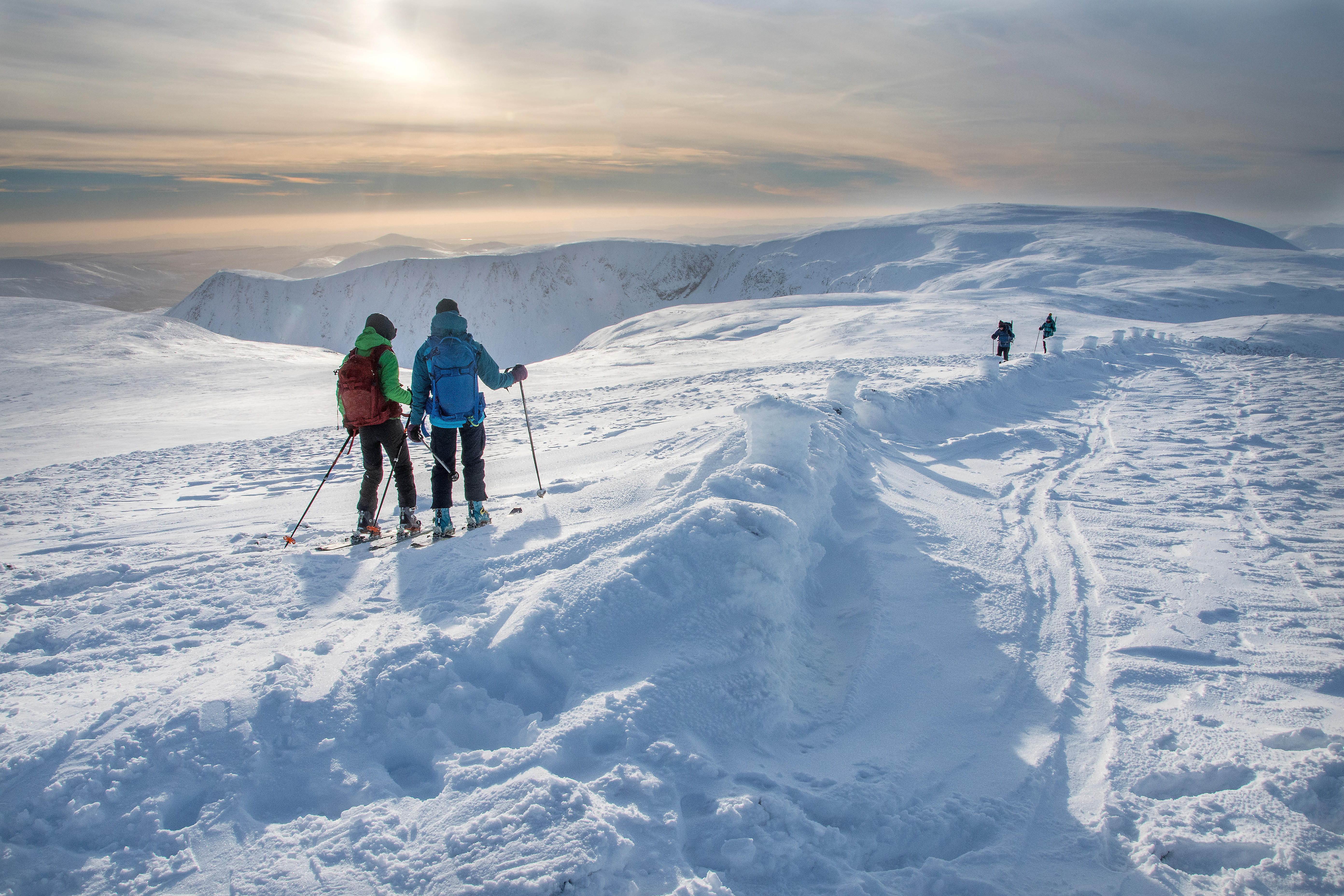 Menschen beim Skifahren im Schnee auf einem Bergrücken.