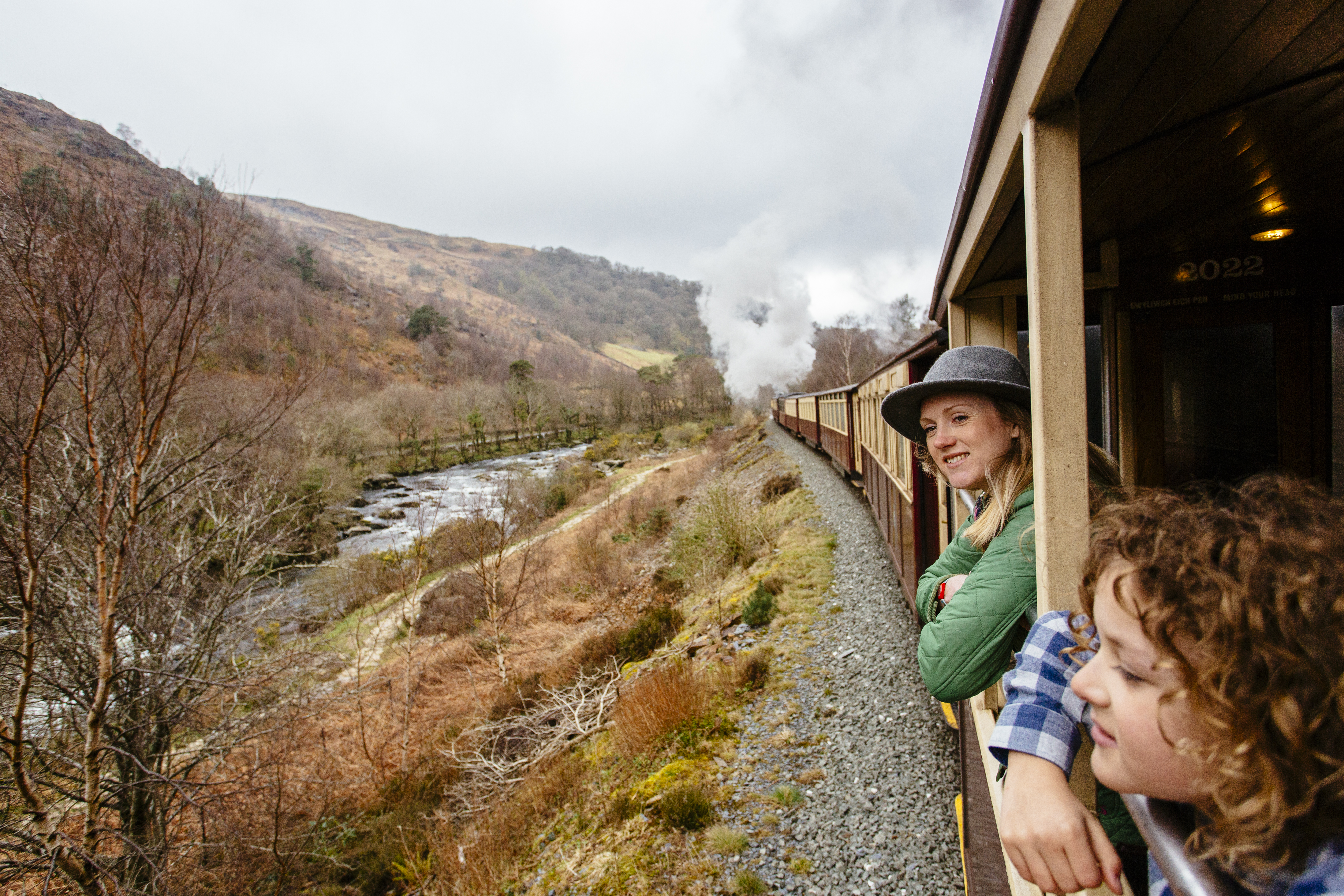 Woman and child leaning out of the window of a steam train