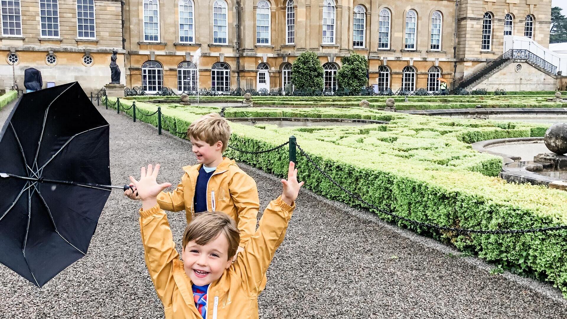 Two children playing in the grounds of a large palace.